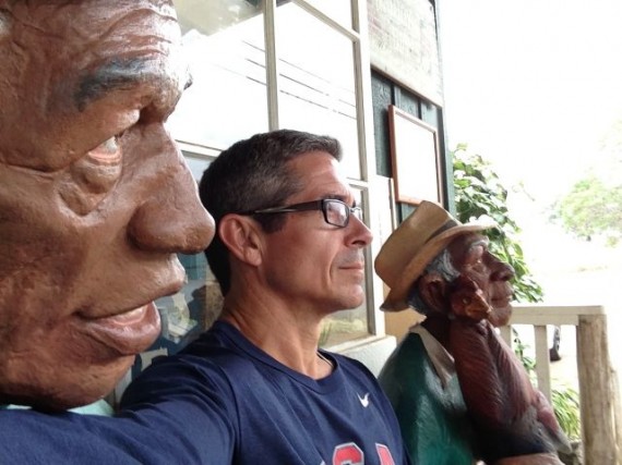 jeff noel sitting between two life-sized human wood carvings