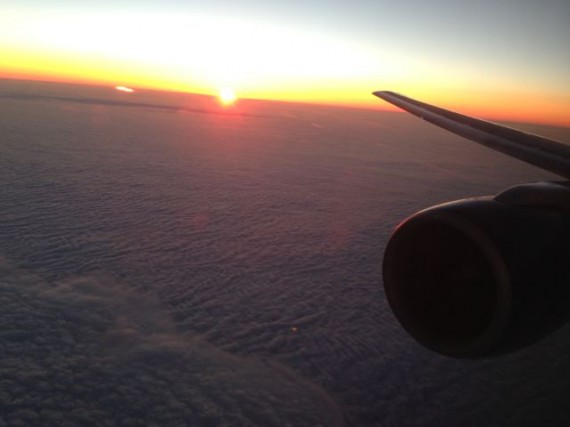 Jet plane cruising above clouds at sunset