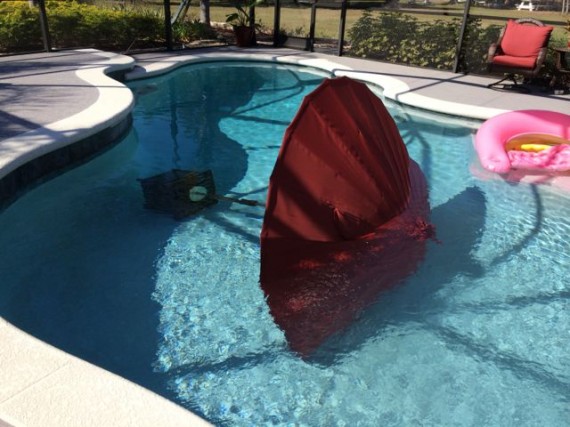 Pool deck umbrella stand blown into pool